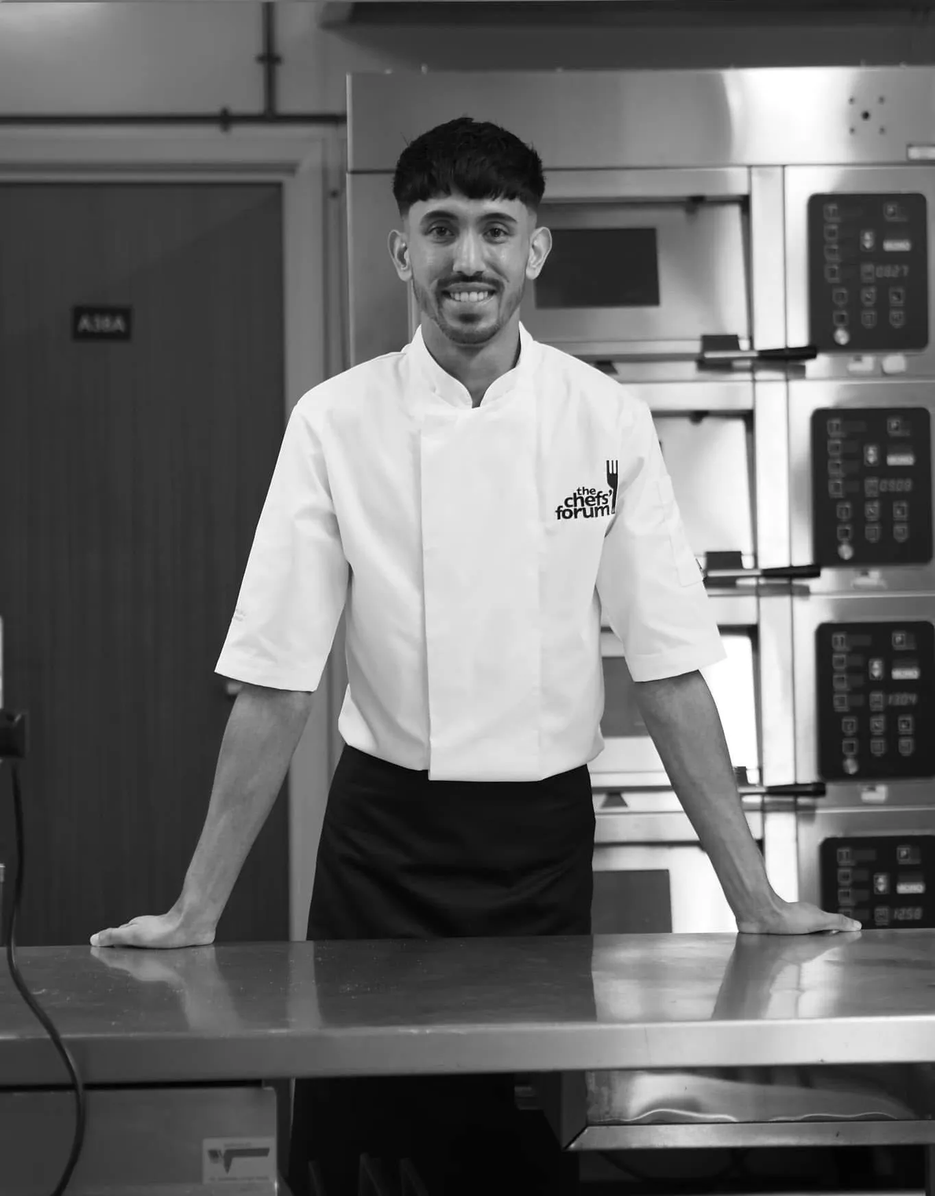 Chef Jubz in a commercial kitchen, monochrome portrait.